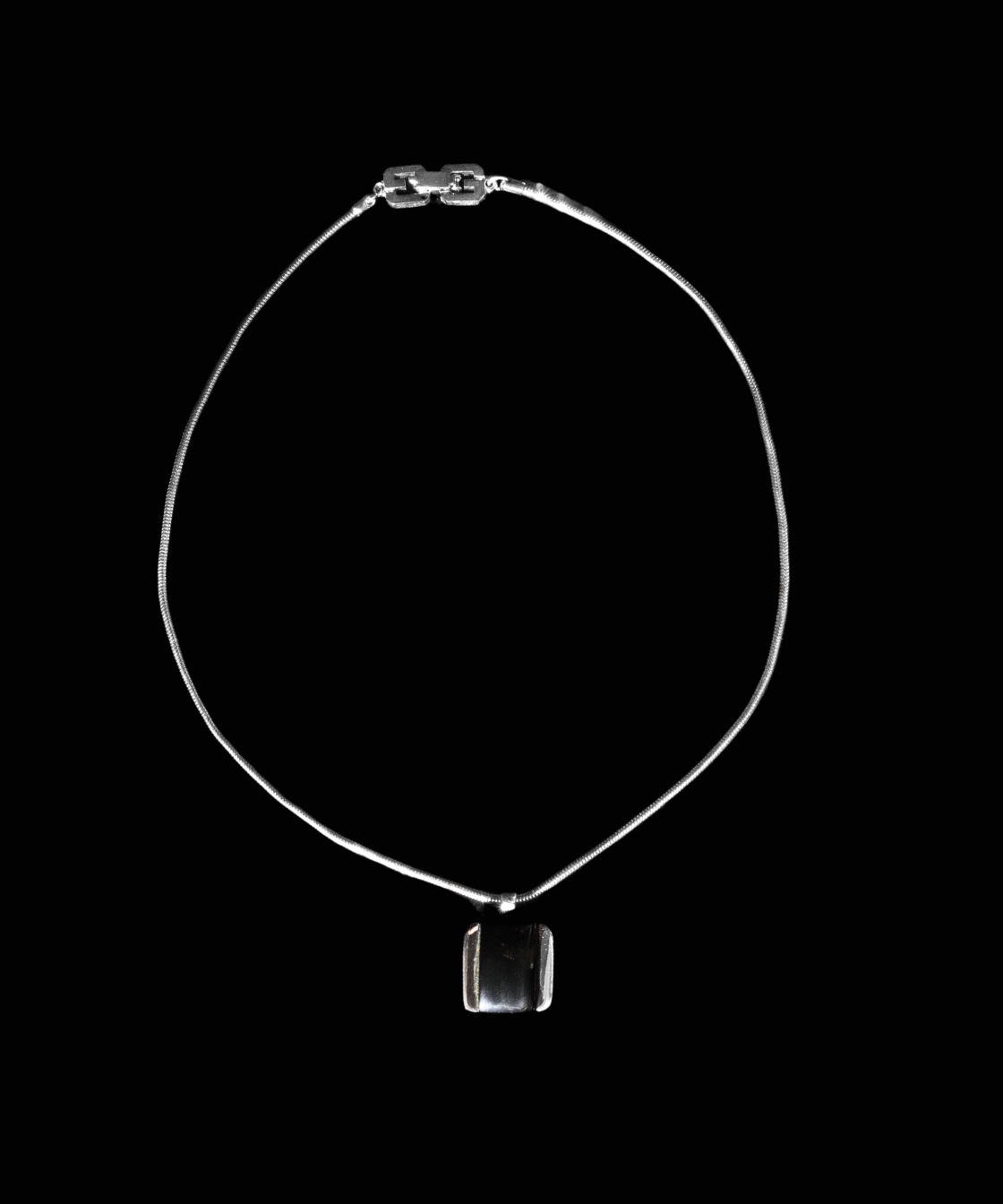 A delicate silver-toned chain Gvenchy necklace with a small rectangular pendant, displayed against a solid black background.