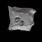 Pair of silver earrings on crumpled paper against a black background
