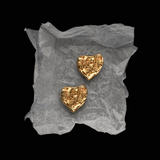 Gold heart-shaped earrings YSL Gold Earrings on a textured gray surface with a black background