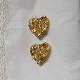 Gold YSL heart-shaped earrings on a white fabric background