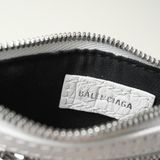 Close-up of the interior of a silver Balenciaga handbag, showing a black fabric lining and a white textured paper brand label sewn onto the inside of the zipper.