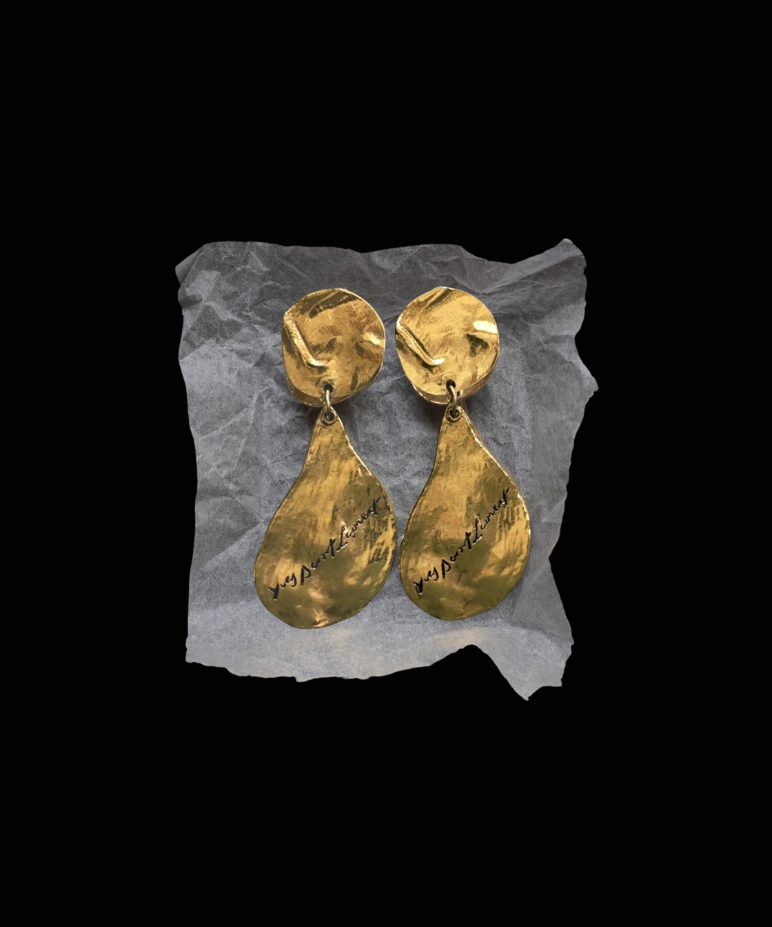 Pair of gold YSL earrings on a black background.