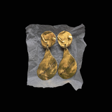 Pair of gold YSL earrings on a black background.