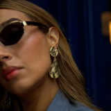 Close-up of a person wearing sunglasses and a blue garment with a blurred background